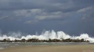 ביום חורפי גל עוצמתי נשבר על שובר הגלים הסלעי, המצלמה הקפיאה רגע מיוחד זה והצליחה להוציאו ורך ועדין. תמונה עם אנרגיה של עוצמה לסלון ביתכם